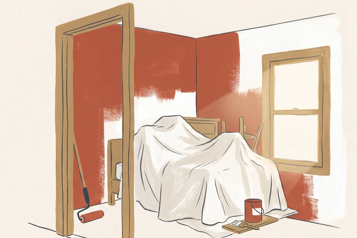 A small bedroom seen from the doorway, furniture covered by a drop cloth, walls half painted terracotta
